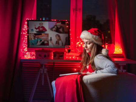 Woman misses her loved ones. Girl in Christmas hat near computer. She speaks with loved ones through...
