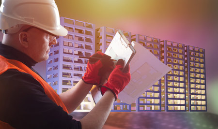 Male engineer at work. Builder engineer draws architectural plan. He works for engineering company. Process of creating engineering drawings. Man builder on background illustration with buildings.の写真素材