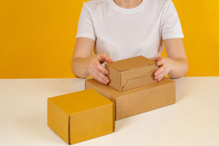 Process of assembling order in the fulfillment center concept. Employee of fulfillment center is packing something. Several boxes in front of girl. Woman works in an order fulfillment center.の写真素材