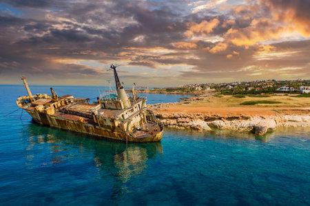 Old ship off coast of Cyprus. Abandoned ship near city of Paphos. Sights of beaches of Cyprus. Rusty ship off Mediterranean coast. Paphos city in background. Holidays in Cyprus.の写真素材