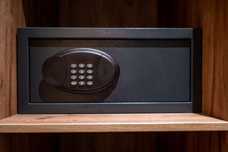 Small metal safe. Safe inside cabinet. Safe with buttons for entering a password. Compact strongbox inside cabinet. It is designed to store valuable items. Concept - purchase of strongbox.の写真素材