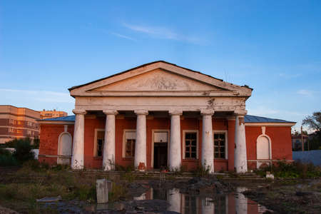 Abandoned building with columns. Concept - was abandoned due to bankruptcy of company. Dilapidated building without windows and doors. House is gradually crumbling from old age. Blue sky backgroundの写真素材