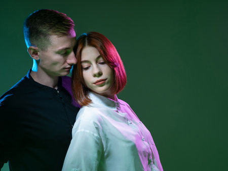 Close-up portrait of loving couple. He presses against her from behind. Married couple concept. Loving man and woman posing on green background. Young married couple is standing nearby. Family photoの写真素材