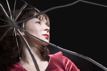 Woman in a stressful situation. Broken mirror as a symbol of stress. Woman is stressed because of the problems. She is in a depressed state. Reflection of a girl in a broken mirror. Displeased girlの写真素材