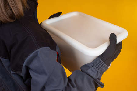 Hands woman picker with box. She collects goods from warehouse. Picker's hands. Girl is an employee of fulfillment center. Woman with plastic box symbolizes picker. Warehouse employee girlの写真素材