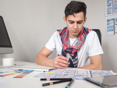 UX design for mobile applications. Web designer at work. A man works in a web studio. UX design for web applications. Mobile app templates in front of designers. Creation of mobile applicationsの写真素材