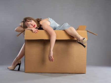 Woman was thrown away as trash. Girl in a cardboard box. Concept - she was used and thrown away. Cruel treatment of women. Violation of girl rights. Abusive family relationships.の写真素材