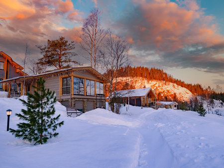 Cottages with panoramic windows in the village. Wooden house on the background of the hills. Snow...