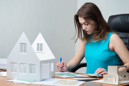 Architect next to the layout of the house. Concept - the workplace of the architect. Girl works with...