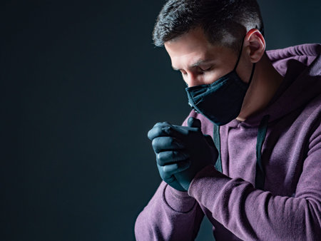 Praying in a medical mask.  Man asks for God's help in treating virus.