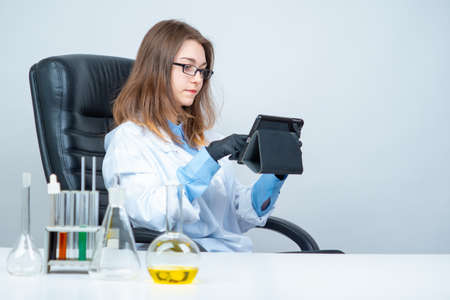 Young girl in a chemical laboratory. Laboratory assistant next to steel with test tubes. Lab technician with a tablet in her hands. Concept - training for a chemist. Career at the medical lab.の写真素材