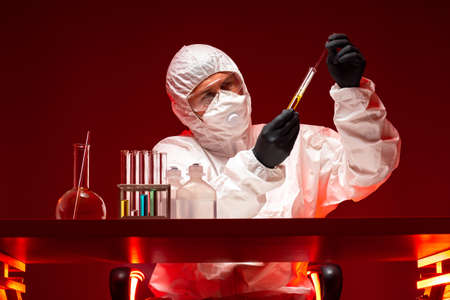 Development chemical weapons. Virologist creates fighting viruses. Concept creation of viruses for conduct of war. Creation of chemical weapons in laboratory. Chemist in chemical protection uniformの写真素材