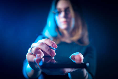 Girl holds out the phone to the camera. A woman passes a smartphone and a stylus. Gadget in the hands of a young girl. Concept - smartphone setup. Concept - phone configuration servicesの写真素材