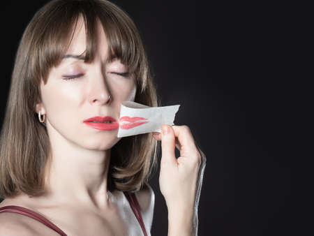 Feminism protest concept. Scotch tape as a symbol of restriction of women rights. Removing tape from mouth symbolizes the feminism protest. Feminist woman face on black background.の写真素材