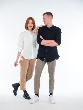 Portrait of a young couple on a white background. Guy and girl are posing side by side. Stylish...