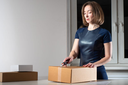 Woman unpacks a cardboard box. She cuts tape on box. Girl received a parcel. She received order from...