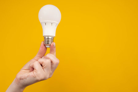 Energy saving. Energy-saving light bulb. LED light bulb. Matte white light bulb in female hand. LED...