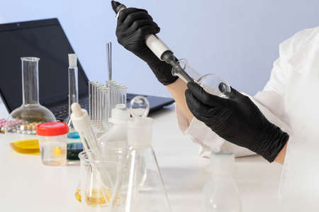 Pharmacology concept. Drug testing. Hands of a lab assistant with flask and pipette. Laboratory employee at work. Hands of chemist, medical laboratory assistant, scientist. Laboratory medical testsの写真素材
