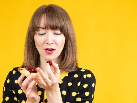 Woman is eating cookies. Girl looks with appetite at cookies with berries. Cookies with berries in...