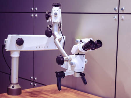 Dental microscope. Electron microscope dantist is mounted on wooden table. Dental operating microscope. Concept - equipment for dental work. Equipment for creation and processing of dentures.の写真素材