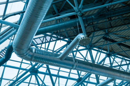 Ventilation pipes in silver insulation material. Ventilation pipes hanging from ceiling inside the...