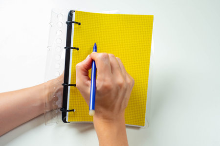 Yellow notepad in female hands. Man writes in a diary. Space for inscriptions on yellow pages. Man...