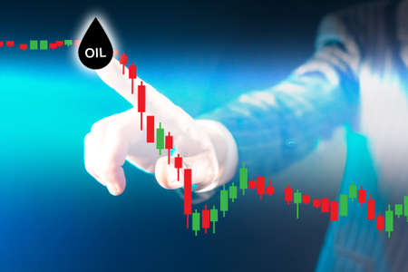 Oil line falls down. Investor fixes beginning of fall in oil prices. He marks place of decline in petroleum products. Blurred hand of businessman next to oil logo. Trader analyzes cost of petroleumの写真素材