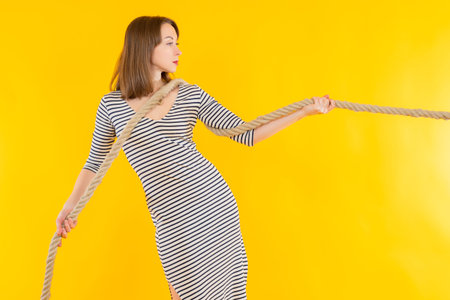The woman is holding a thick rope. Concept - she's trying to drag it with a rope. The girl is...