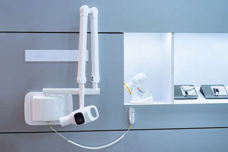 Dental equipment x-ray in clinic. X-ray machine in dental office. Intraoral high-frequency X-ray machine is mounted on wall. Equipment for creating picture of human teeth. Dental apparatus.の写真素材