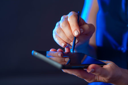 Woman with smartphone. Phone in hands close-up. Girl controls phone with stylus. Smartphone app...