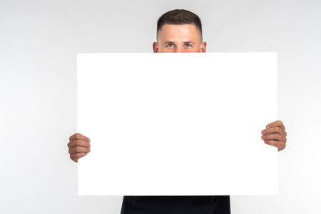 Man with white banner. He shows blank sheet of paper in near of him. Portrait man with a closed...