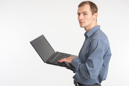 Man with laptop. Guy in a plaid shirt stands and holds laptop in his hands. Place for text on the...