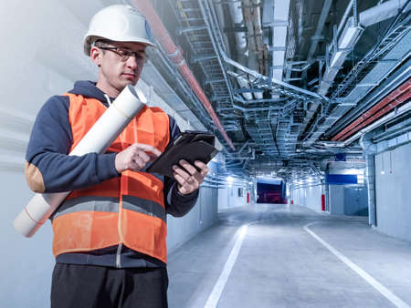 Design of engineering systems and communications. A builder or engineer with drawings in building. Design of ventilation systems in buildings. Engineering communications in industrial premises.の写真素材