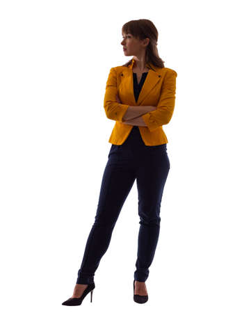 Stylish businesswoman. Businesswoman on a white background. Portrait of a woman in full post. Businesswoman in a yellow jacket and high heels. She looks to side with her arms crossed.の写真素材