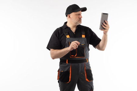 Man worker in a blue uniform. Worker with electronic tablet in his hands. Adult man with tablet...