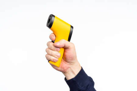 Infrared thermometer. Yellow handheld thermometer is pointing up. Human hand with medical gadget. Medical equipment sale concept. Non-contact thermometer for measuring human temperatureの写真素材