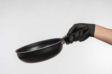 Small frying pan in hand. Man holds frying pan in front of him. Man's hand holds out frying pan with removable handle. Concept - sale of cookware for hot processing. Anti-stick cookwareの写真素材