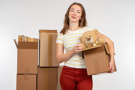 girl with boxes just moved. She is holding box with toy and looking at camera. Metaphor of change of...