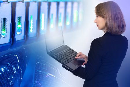 Woman sysadmin. System Infrastructure Manager. Girl is network service specialist. Server hardware next to her. Woman IT manager during work. Girl programmer with laptop. System administrator careerの写真素材