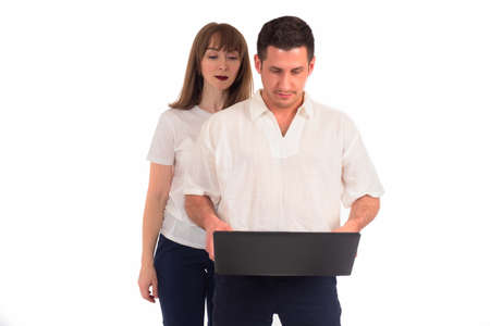 Two office workers with laptop. Concept male master of computer settings. Computer repair. Laptop repair technician. Man sets up computer for girl. Man and woman stand with laptop on white backgroundの写真素材