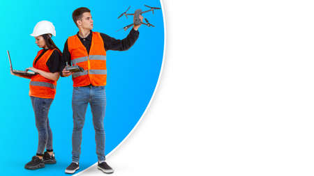 Drone operators. Two operators with drone in their hands. Guy and girl are driving quadcopter. They launch drone for filming. Professional quadcopter operators. Copy space on white backgroundの写真素材