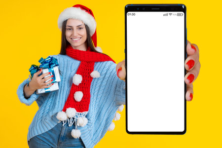 Christmas mobile app. Happy woman demonstrates smartphone with white screen. Girl with big phone....