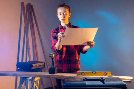 woman is doing home repairs. She makes her own repairs. Woman builder in casual uniform. Construction tools in front of girl. Repairer girl with work tools. Portrait of repairer womanの写真素材