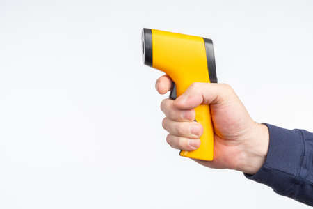 Non-contact thermometer in hand. Human hand with portable thermometer. Device for measuring temperature. Yellow portable thermometer on white background. Place for your text. Medical equipmentの写真素材