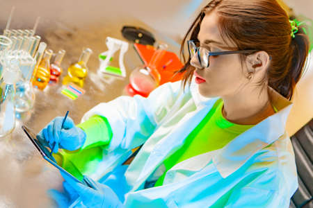 Girl chemist in the laboratory. Environmental control. Chemical laboratory. Research. Girl with a tablet in a chemical lab. Work as a chemist. Chemistry education. Laboratory work in chemistry.の写真素材