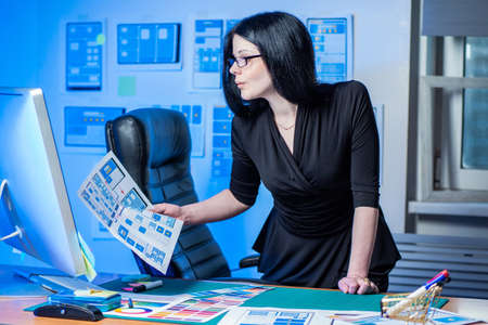 Creation of applications. Head of designer studio. Coordination of design with the customer. Cabinet of app developers. Web design. Coordination of site design. Woman in the office of web designersの写真素材