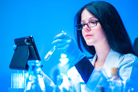 Girl with a test tube and a tablet. Pharmacist. Woman in the laboratory. The study of drugs....