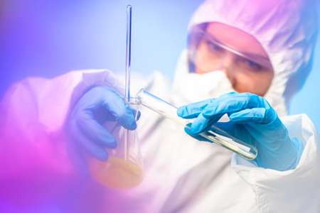 Chemical laboratory. Work with hazardous materials. Chemist in a respirator. Safety rules in the laboratory. A man holds test tubes in his hands. A person conducts chemical experiments.の写真素材