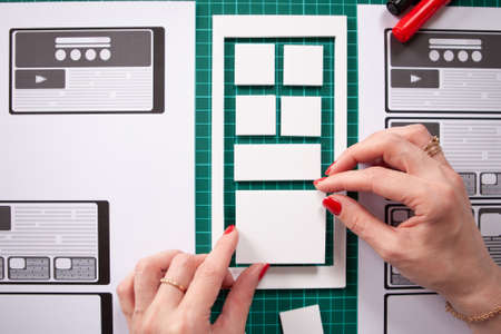 Girl creates a prototype application. UX mobile app design. The process of creating an application. Visualization for phone applications. She thinks the structure of the application designer.の写真素材