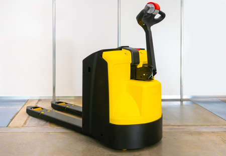 Electric pallet transporter. Cargo trolley. Loader. Electric trolley. Work in a warehouse. Transportation of goods. Pallet carrier escorted. Modern equipment for the warehouse. Warehouse Stacker.の写真素材